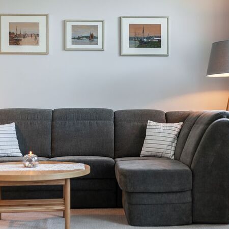 Appartement Gloria - Gemütliches Wohnzimmer mit grauem Sofa und Kunstwerken an der Wand