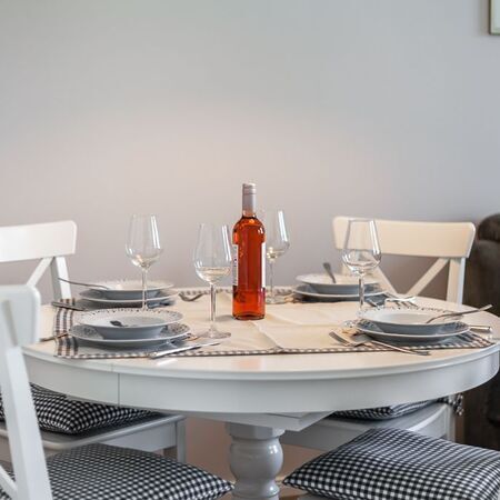 Appartement Gloria - Eleganter Esstisch mit einer Flasche Roséwein und Gläsern