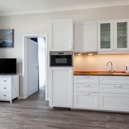 Appartement Gloria - Eine moderne Küche mit weißen Schränken und Holzarbeitsplatte