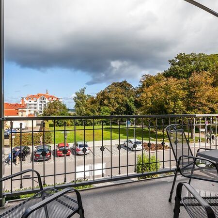 Appartement Gloria - Blick vom Balkon auf den Park mit Bäumen und Autos