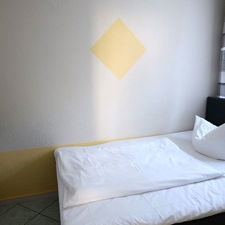 Modernes Schlafzimmer mit weißen Bettwäsche und dekorativer Wand