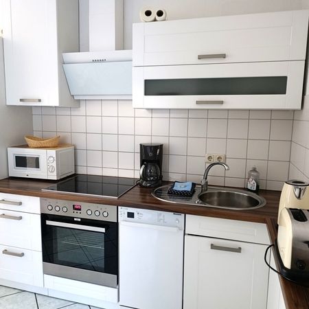 Elegante Küche mit Holzarbeitsplatte und modernen Geräten