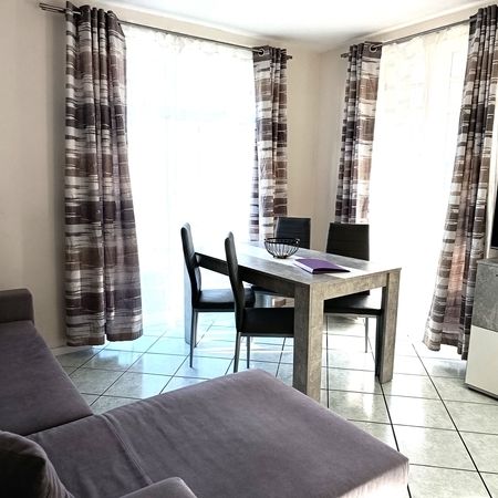 Wohnzimmer mit Fernseher, Tisch und Stühlen