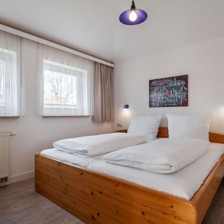 Komfortables Schlafzimmer mit einem Holzrahmenbett und moderner Dekoration