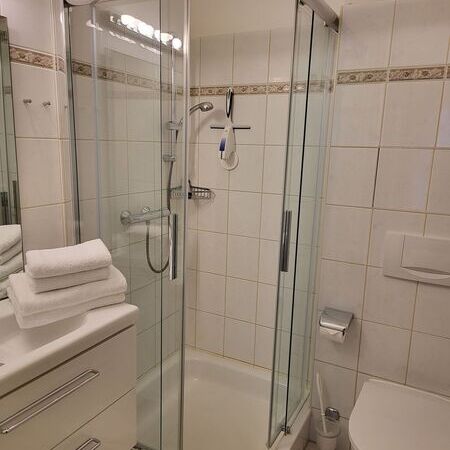 Badezimmer mit eleganter Glasdusche und Handtüchern