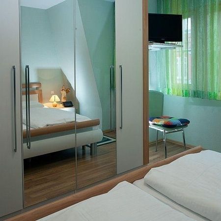 Modernes Schlafzimmer mit Spiegel, Fernseher und buntem Stuhl