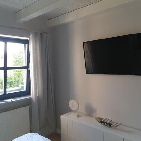 Elegantes Schlafzimmer mit Wand-TV und stilvollem Dekor