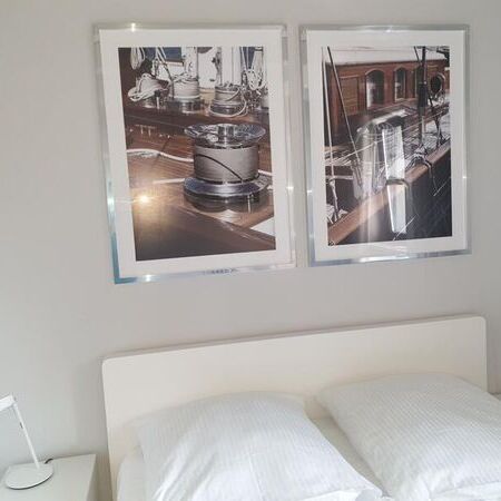 Modernes Schlafzimmer mit maritimen Bildern an der Wand