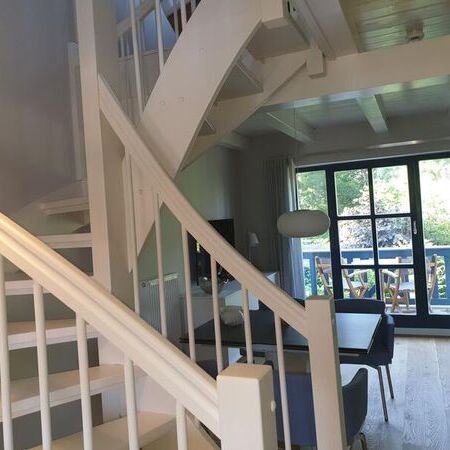 Helles Wohnzimmer mit einer eleganten Treppe und großen Fenstern