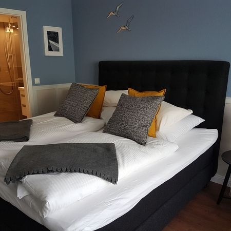 Das Bett im Doppelzimmer 101 mit grauen Kissen