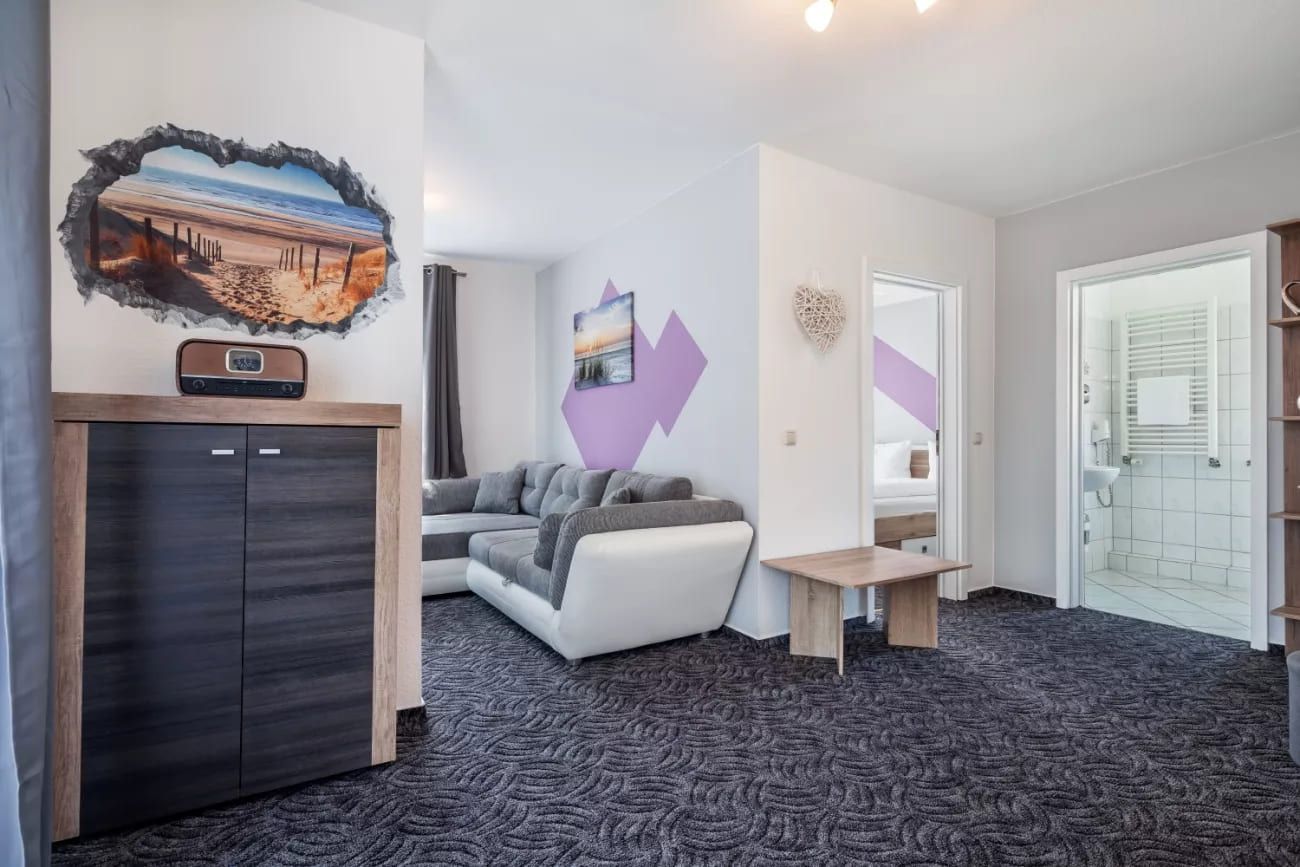 TW 112 Rosenhof - Gemütliches Wohnzimmer mit Strandmotiv an der Wand und moderner Einrichtung