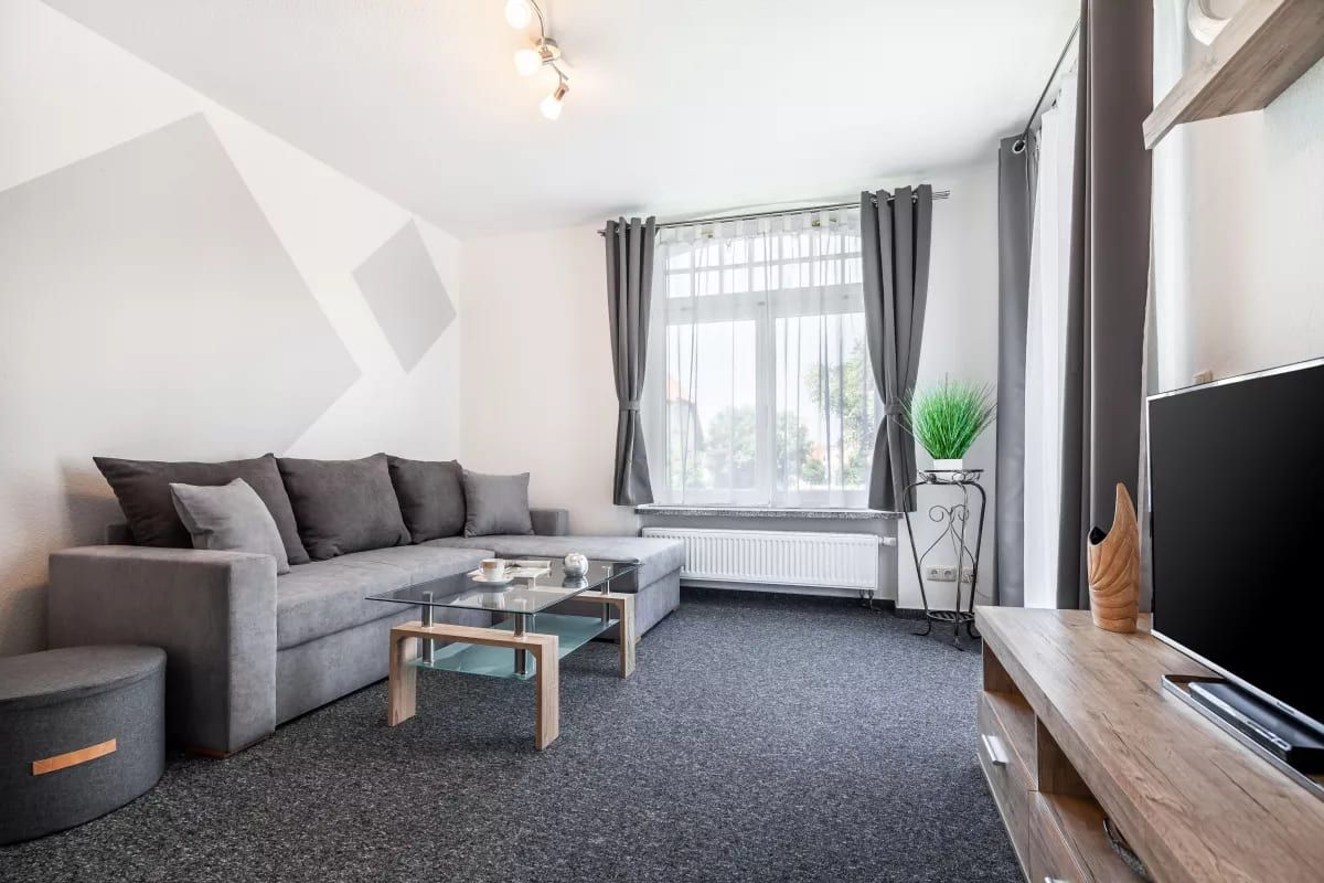 TW 113 Rosenhof - Modernes Wohnzimmer mit grauem Sofa und Glas-Tisch