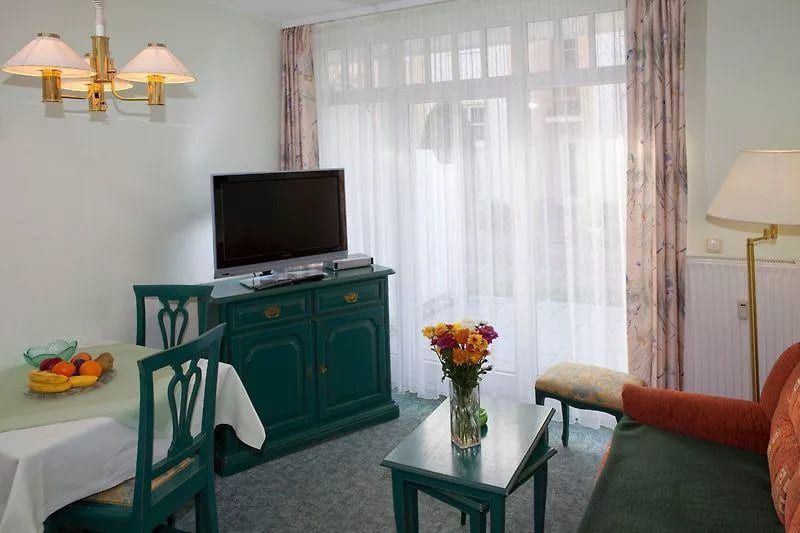 Nr. 02 Rosenhof - Wohnzimmer mit Fernseher, Esstisch und bunten Obstschalen