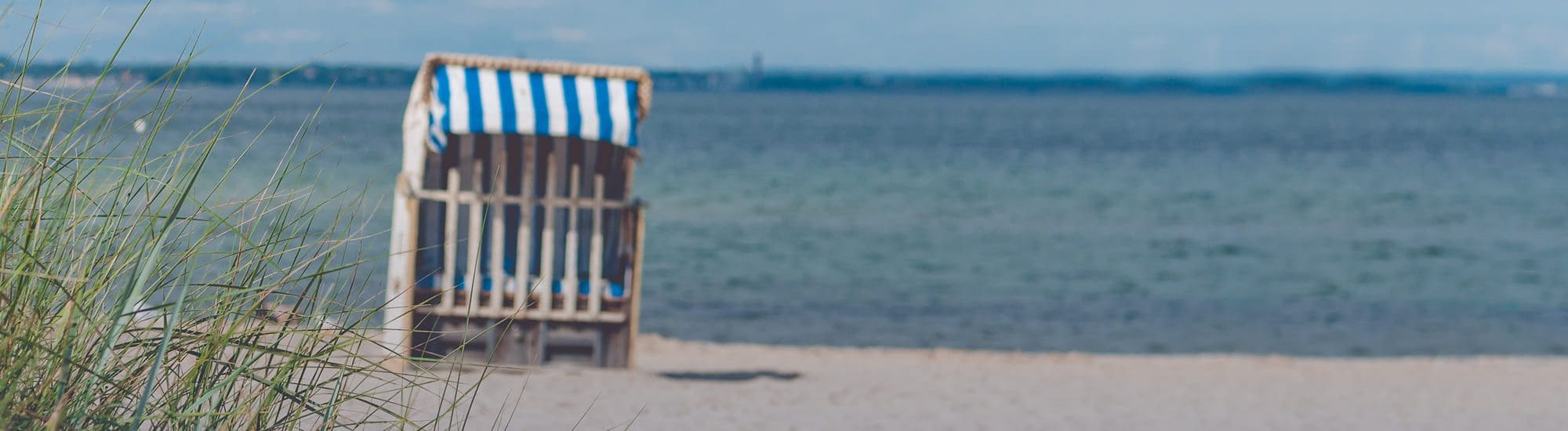 Eine Nahaufnahme eines Strandes mit einem Strandkorb und dem Meer im Hintergrund